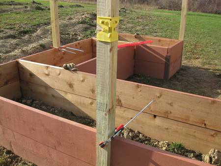 In the garden, a yellow post level is fixed on the wooden post with elastic strap.